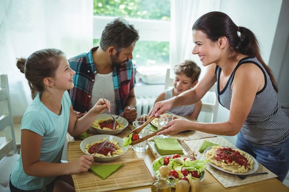 Smiling woman serving meal to her family at home