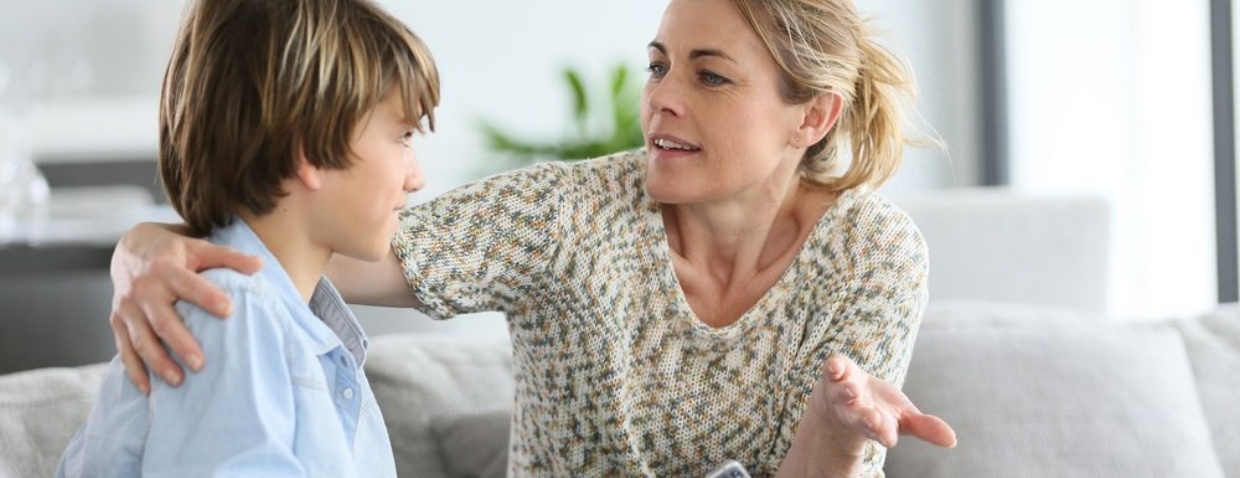 Mother giving warning to young boy using smartphone Mother giving warning to young boy using smartphone