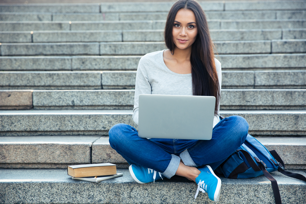 Portrait of a happy young woman sitting on the city stairs and using laptop computer outdoors-1 Portrait of a happy young woman sitting on the city stairs and using laptop computer outdoors-1