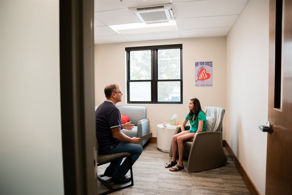 Teen mental health counseling session showing therapist supporting adolescent with depression and anxiety