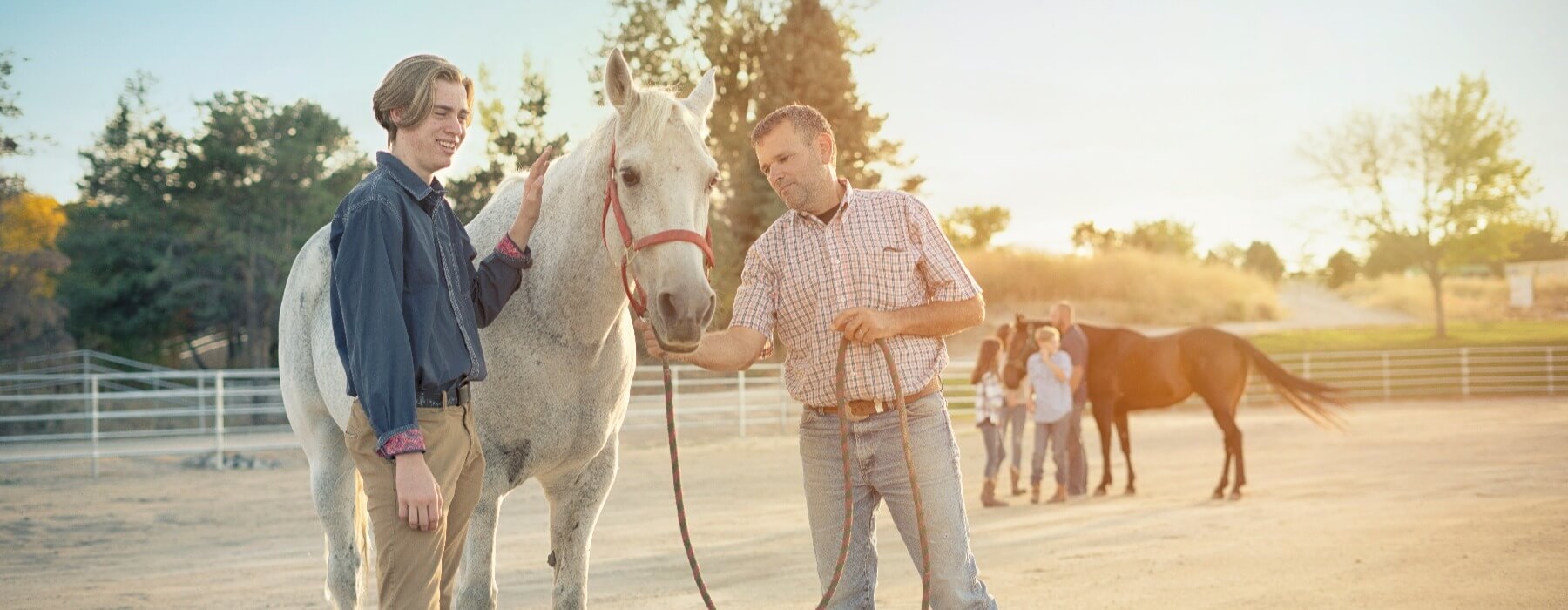 father and teen petting horse
