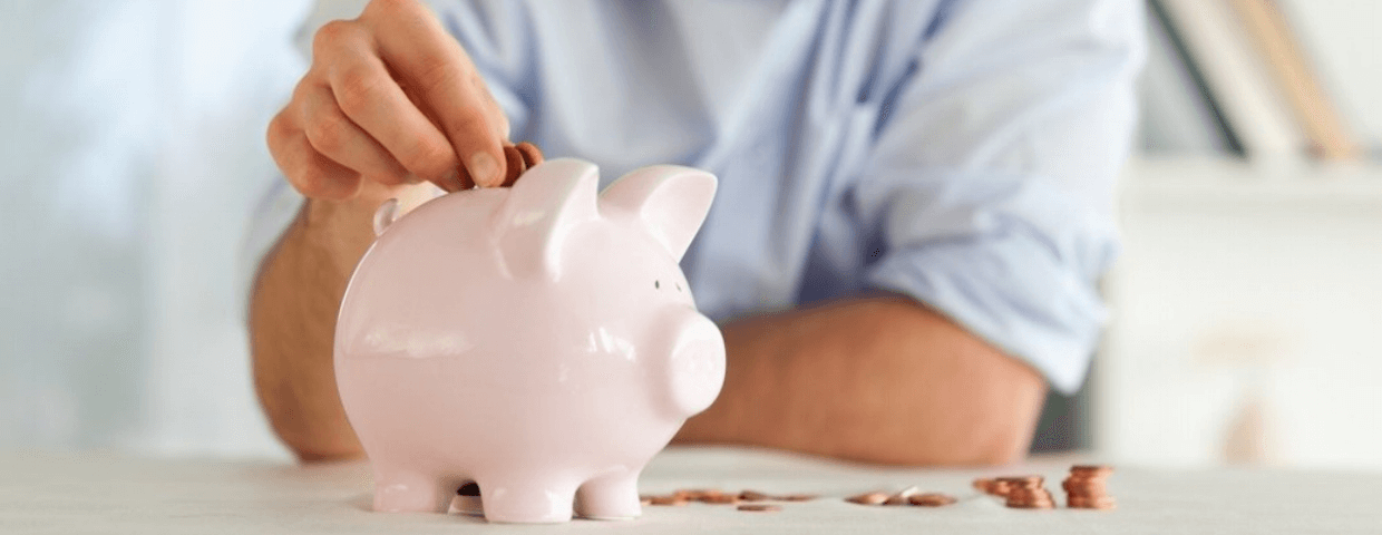 man putting money in piggy bank