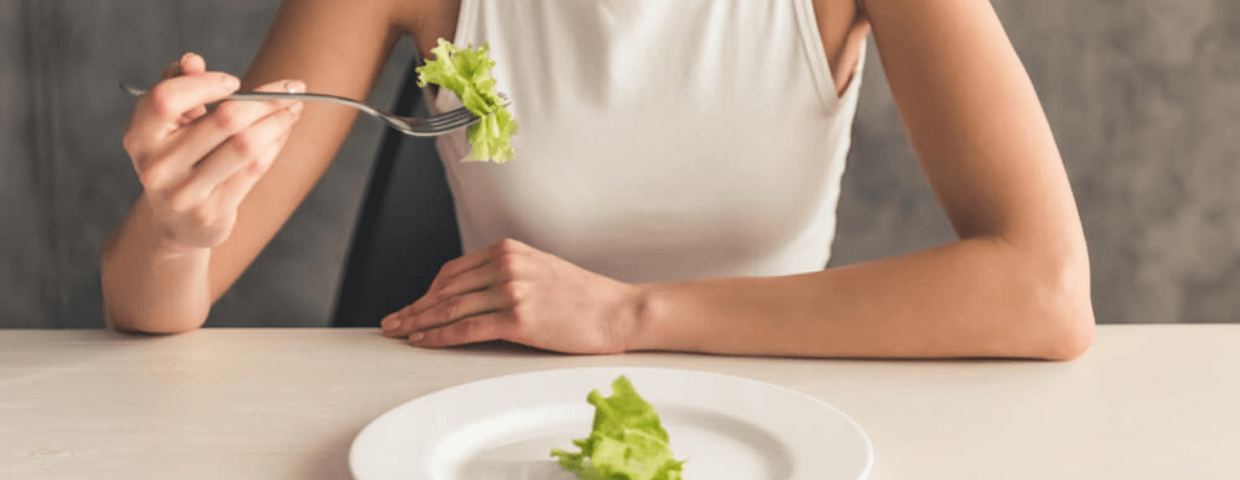 teen eating disorder concept, teen at table eating one single piece of food