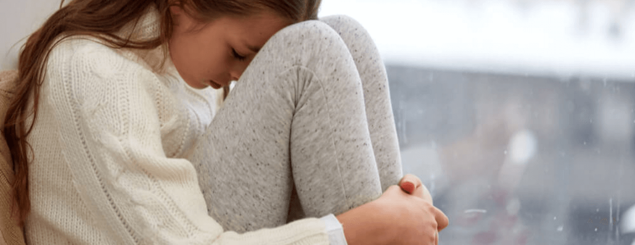 teen girl sitting with her head on her knees, upset, dislike or hate school concept