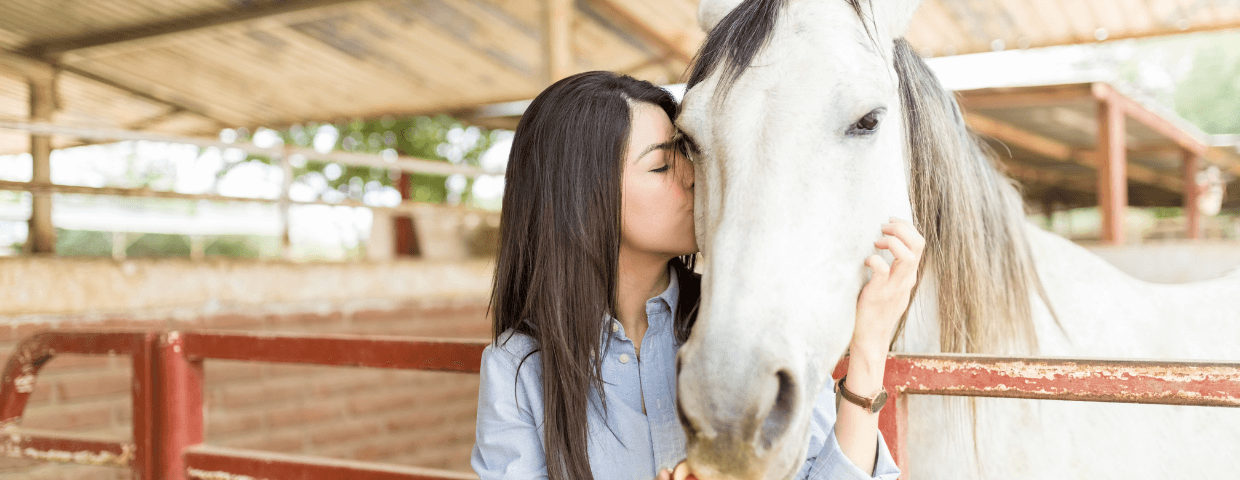 a teenager girl wrapping arms around her horse
