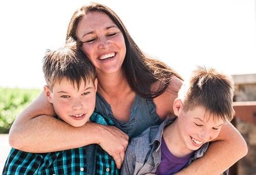 Mom holding sons and smiling