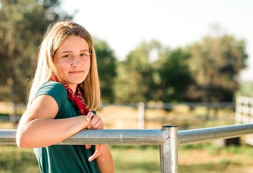 Smiling girl leaning against a fence