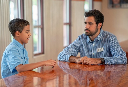 Man sitting at a table talking with a little boy