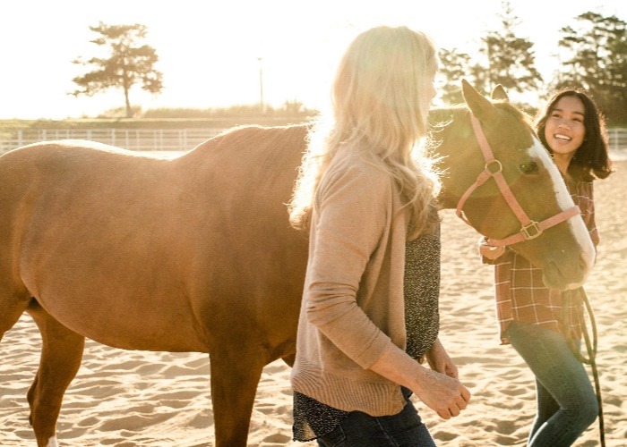 two women walking with horse