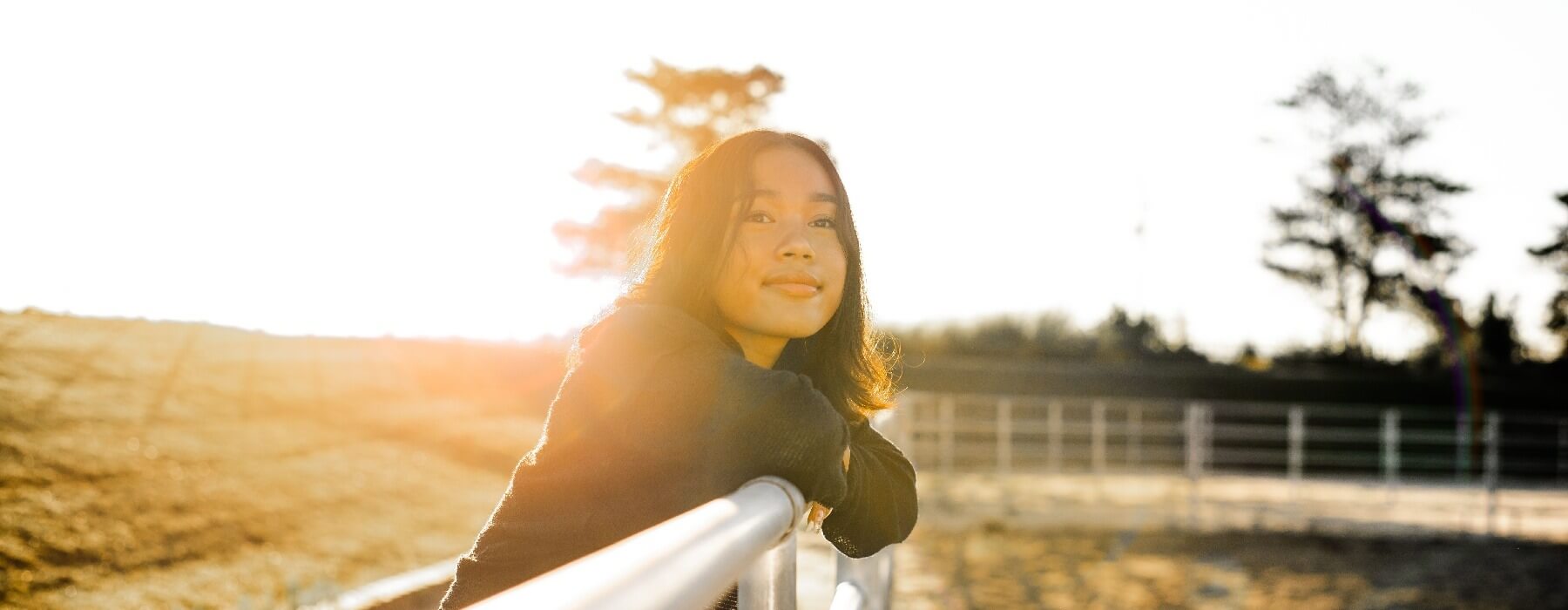 happy teen girl with sunrise behind her